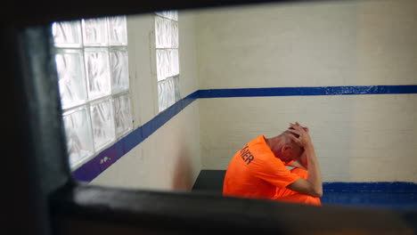 a depressed prisoner is sitting in his cell