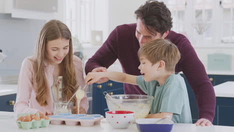 Padre-Con-Dos-Hijos-En-La-Cocina-De-Casa-Divirtiéndose-Horneando-Pasteles-Juntos