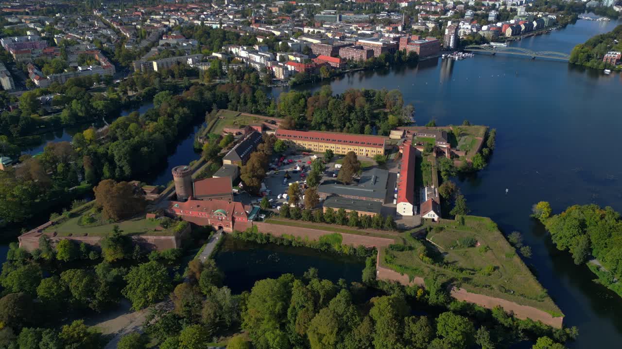 Spandau Citadel, an imposing Renaissance fortress surrounded by water, stands under a clear sky. Best aerial view flight drone camera pointing down