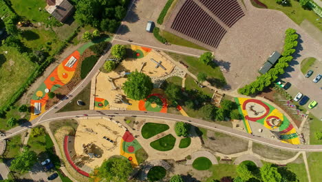 Vista-Aérea-De-Los-Coloridos-Parques-De-Uzvaras,-Con-Juegos-Infantiles-Y-árboles-Verdes-En-Jelgava,-Letonia