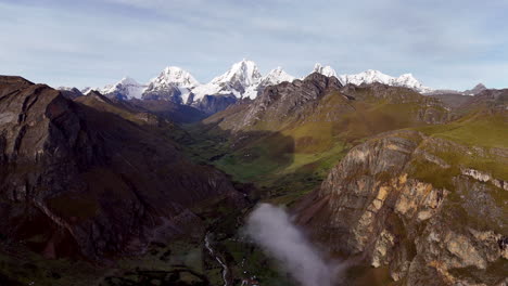 Cinematic aerial view of snowy Andes mountains in Peru with glaciers, rocky cliffs, and hidden blue alpine lake under misty clouds, dramatic landscape and natural travel destination