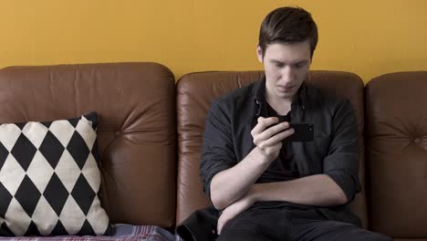 young man using a smartphone on a couch