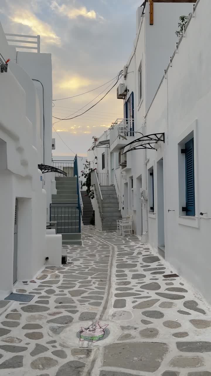 una serena calle de adoquines de estilo cicládeo con edificios encalados durante el amanecer temprano en paros.