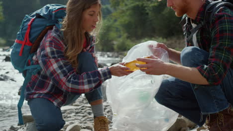 Volunteers-collecting-bottles-on-river-shore.-Hikers-cleaning-river-from-trash