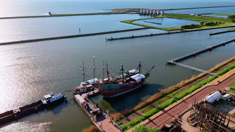 Old-style ship and modern motorboats standing on the anchor. Reconstruction of the VOC ship Batavia at Museum Batavialand, Lelystad, the Netherlands. Aerial perspective.