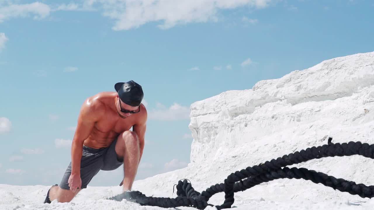 Athletic man doing fitness exercises with a rope in nature. Slow motion