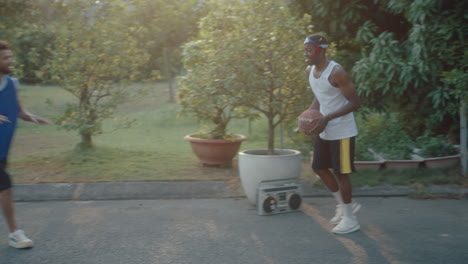 two young guys playing basketball on outdoor court during golden hour