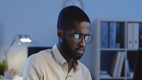 very tired man working at the computer in the office at night, then taking off his glasses