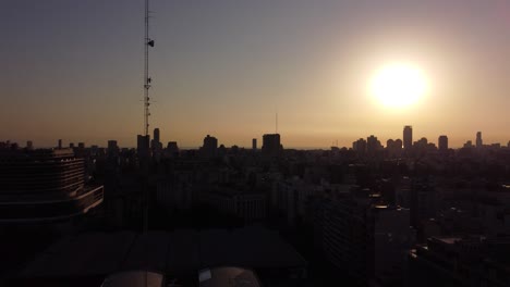 aerial shot showing silhouette of skyscraper buildings and tv televion antenna during sunrise