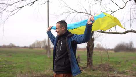 man with the flag of ukraine near the burnt tree