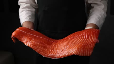 chef sosteniendo un pedazo de salmón crudo