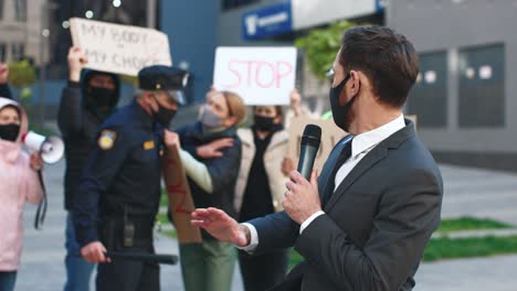 caucasian journalist or correspondent wearing protective mask giving interview in a protest against covid 19