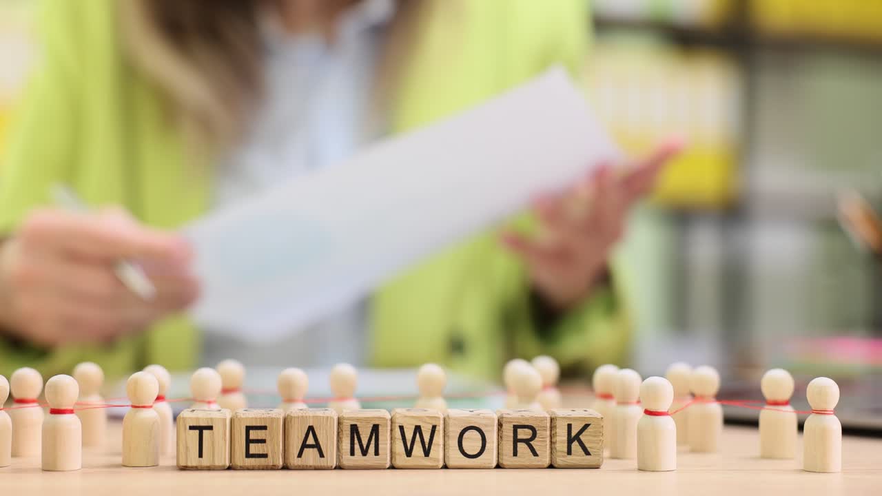 Wooden blocks spell teamwork as manager reviews planning notes