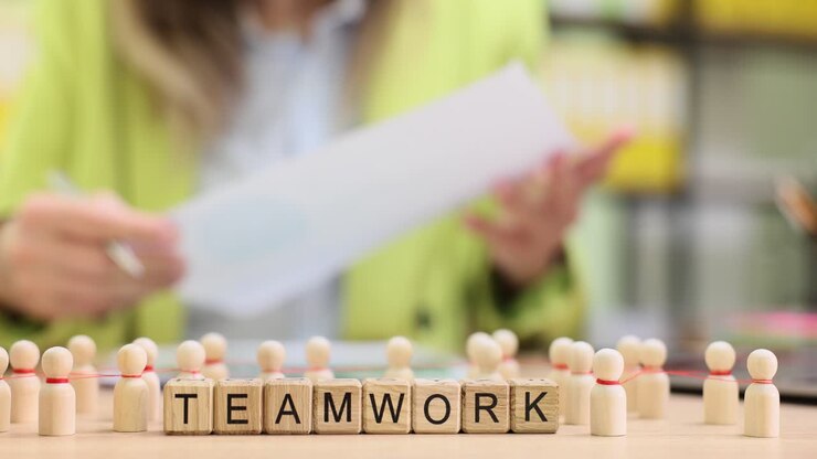 Wooden blocks spell teamwork as manager reviews planning notes