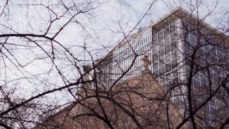 right-panning-shot-of-Sabadell-bank-company-building-behind-tree-and-catholic-church-in-barcelona-city-spain