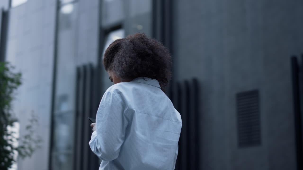 Joyful woman reading message posing alone at modern building. Successful manager