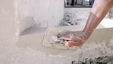 manual worker's hand plastering wall using hand trowel at construction site