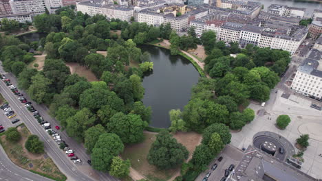 Mirando-Hacia-Abajo-Desde-El-Cielo,-Encontrarás-Ørstedsparken-Ubicado-Entre-Los-Edificios-De-La-Ciudad,-Con-Su-Hermosa-Vegetación-Y-Lagos-Serenos