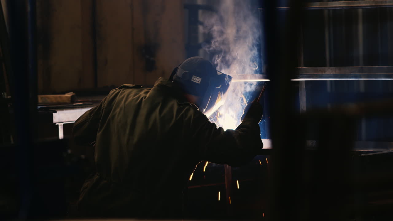 A welder in a protective helmet and clothes welds as sparks fly 7