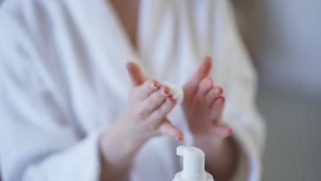 hermosa mujer joven aplicando espuma de limpieza en la cara en el baño