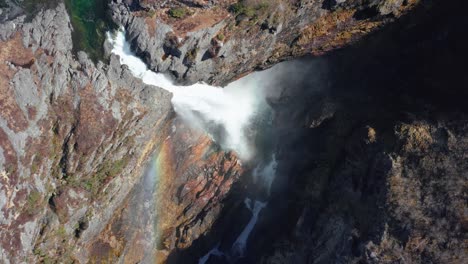 High-Angle-Aerial-View-of-Glacial-River-Waterfall-and-Rainbow-Above-Splashes