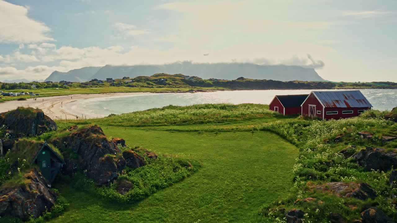Aerial drone shot of the picturesque green landscape of the Lofoten islands, Norway. Bird's eye view of the white sanded beach and the turquoise Norwegian Sea. Unspoiled nature, natural wonder.
