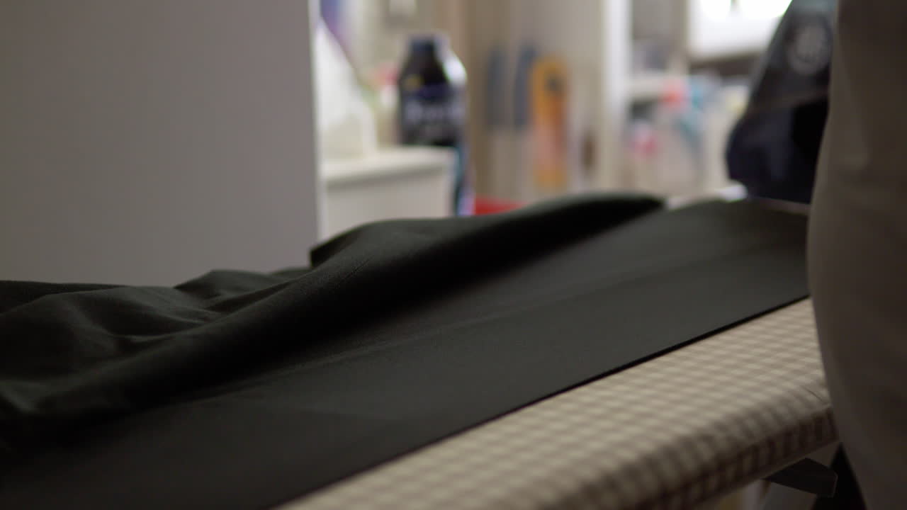 Someone irons trousers with an electric iron