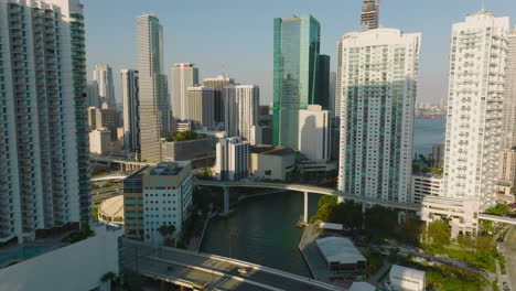 Forwards-fly-above-river-and-along-modern-residential-buildings.-Revealing-downtown-skyscrapers.-Miami,-USA