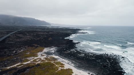 Toma-Aérea-De-La-Exótica-Playa-De-Arena-Negra,-Océano-Ondulado-áspero-4k