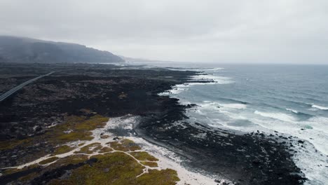 toma aérea de la exótica playa de arena negra, océano ondulado áspero 4k