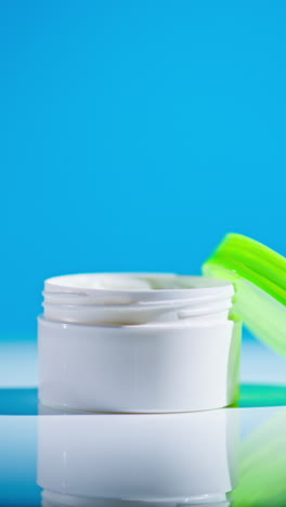 open white plastic jar of cream with green lid