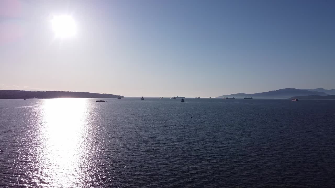 화물선이 상업 부두에서 수출품 석유 원료를 수입하기 위해 줄을 서서 태양이 산비탈 바다 전망에서 계속 빛나는 동안 버라드 입구에서 일몰을 공중으로 잡습니다.