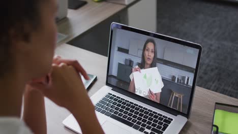 African-american-businesswoman-sitting-at-desk-using-laptop-having-video-call-with-female-colleague