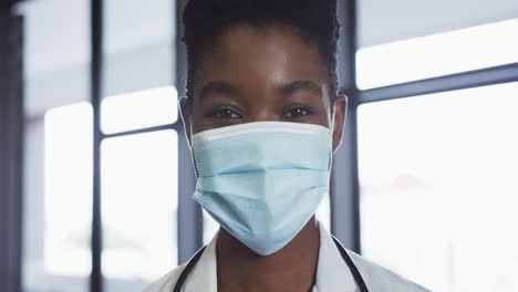 portrait of african american female doctor wearing face mask looking at camera