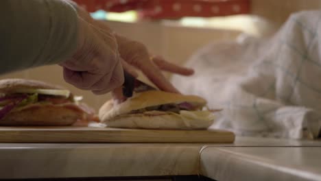 woman's hands cutting prepared sandwiches in kitchen medium shot