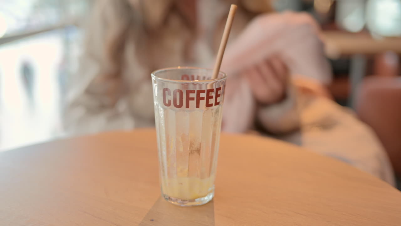 Close up of an empty glass with a straw with a coffee writing on it
