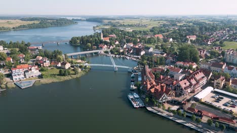 mikolajki, poland - aerial bird view flight over the pedestrian bridge most wiszacy of the touristic city in warmian masurian with romantic houses along the sea and tiny ships and yachts in summer