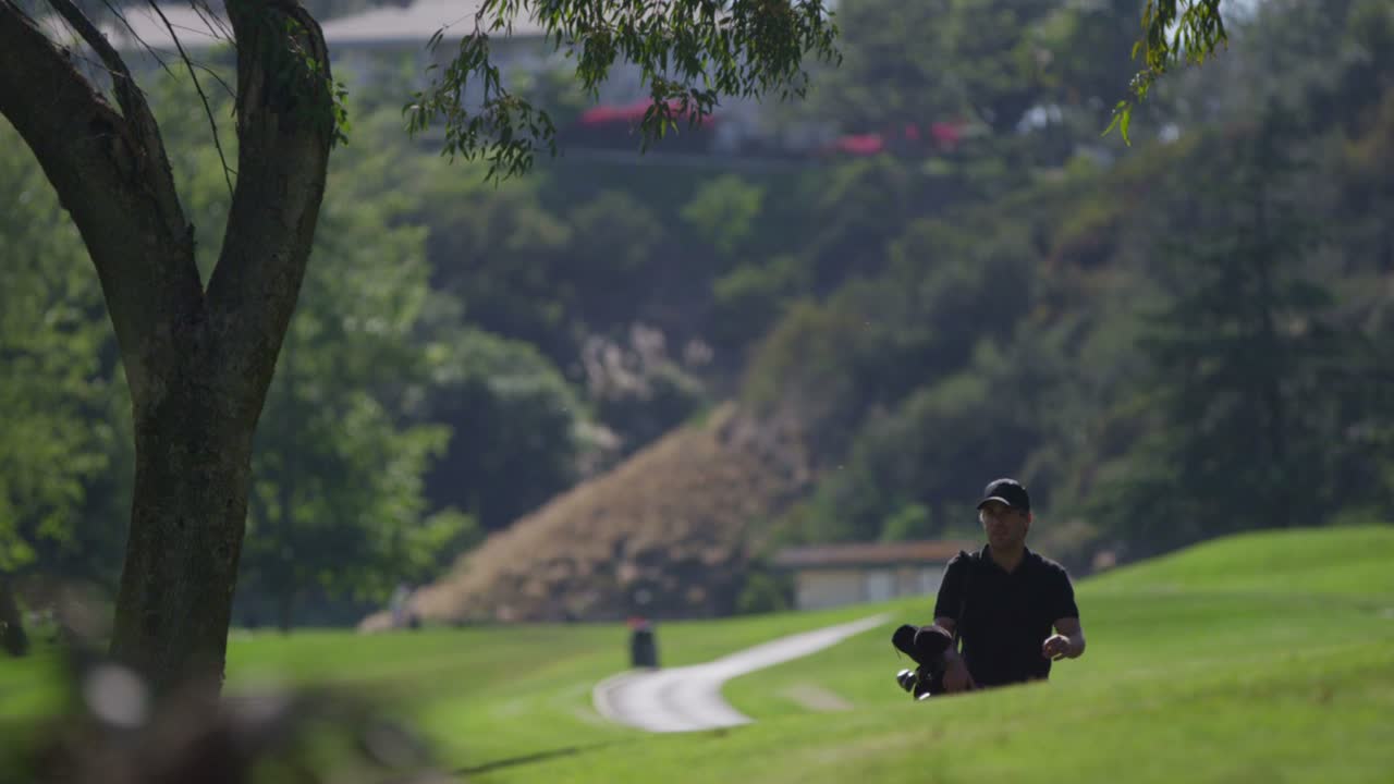 골퍼가 골프 코스의 언덕을 걸을 때 클럽을 들고 다닙니다.