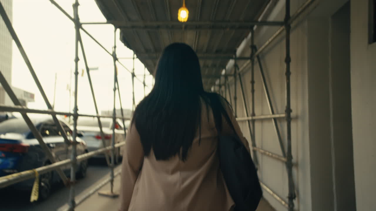 Woman walking under scaffolding in city