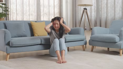 폭력의 희생자인 젊은 아시아 여성의 몸이 가득 차 있고, 몸에 이 있고, 신경약을 고, 집에서 바닥에 앉아서 비명을 지르고 있다.