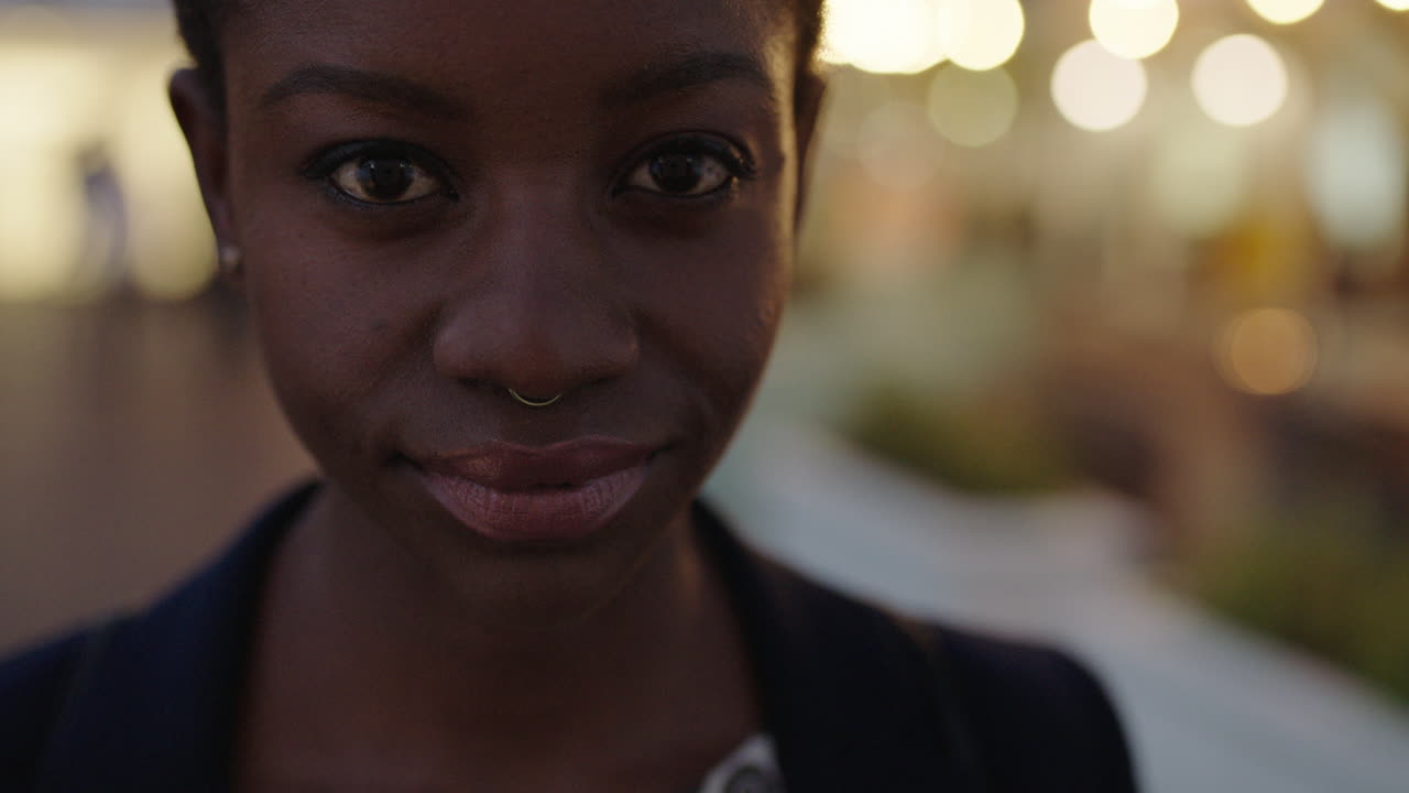 close up portrait of beautiful african american business woman looking at camera serious confident wearing nose ring in evening city background light bokeh