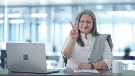 feliz mujer de negocios india senior mostrando el signo de la victoria