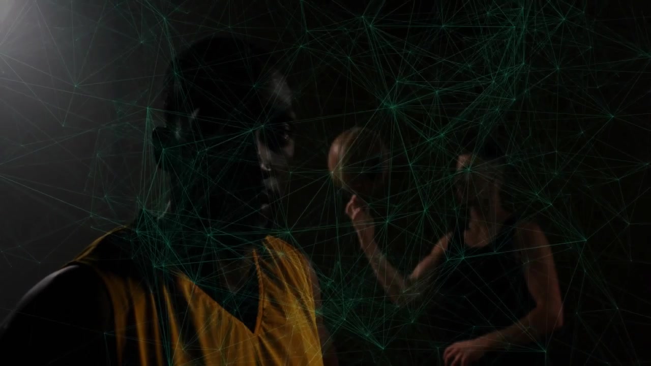Two basketball teammates practicing sports tech in dark studio projecting green network around ball