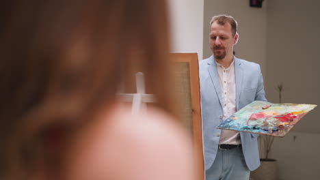 an artist showing a student how to use different colors on a palette