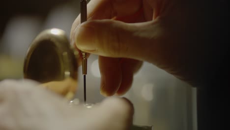 person using fine tool to work on a pocket watch