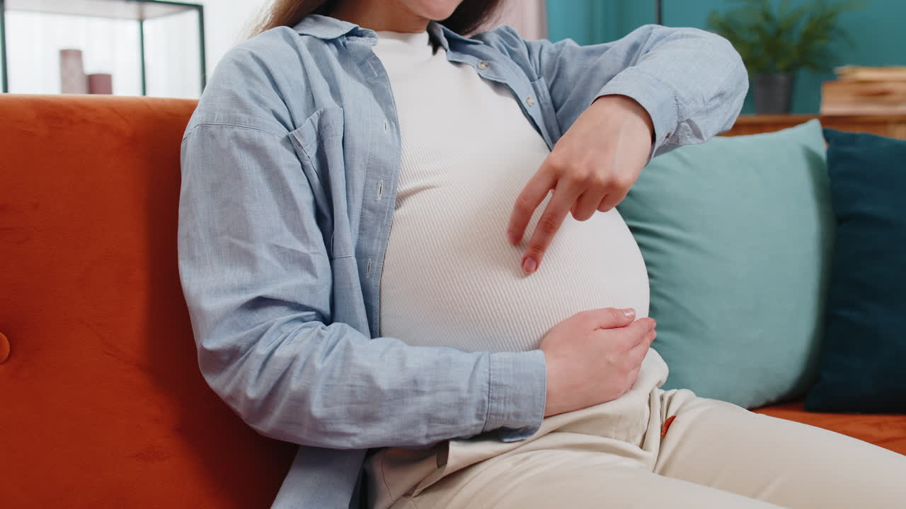 Happy pregnant woman walks her fingers over her large belly expecting baby playing with unborn child