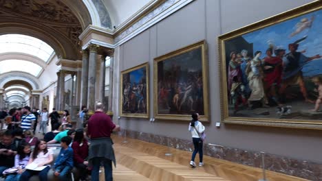 los visitantes admiran pinturas en el museo del louvre