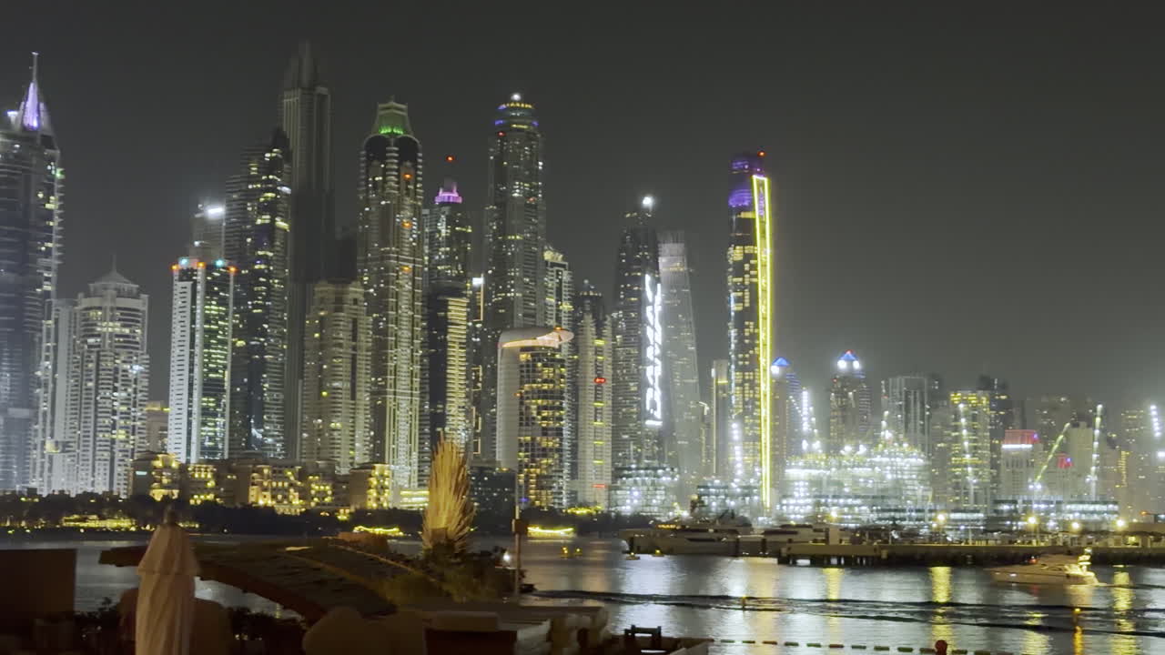La città di Dubai di notte, skyline illuminato con riflessi magici sul lungomare della marina da