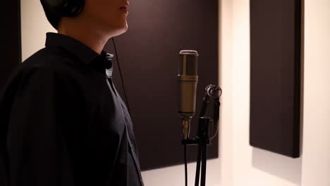 person wearing headphones recording vocals in a professional studio with a microphone