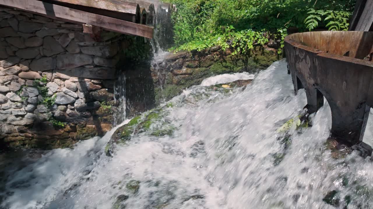 Splashing white water cascades from wooden sluice flume construction, slow motion